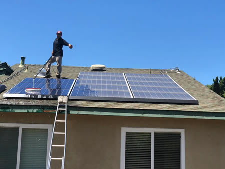 Technician rinsing rooftop solar panels in san jose afternoon sun
